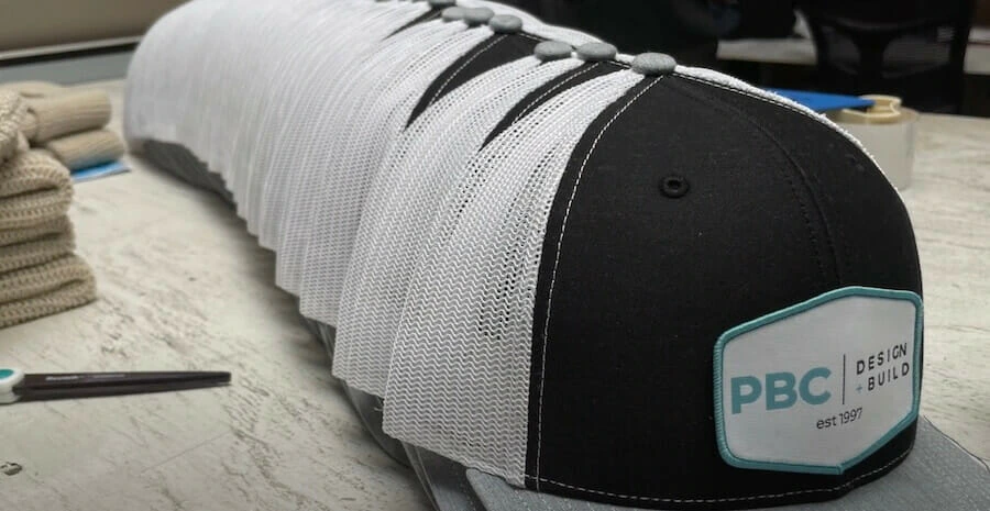 custom made hats sitting in a row with PBC design build logos on them
